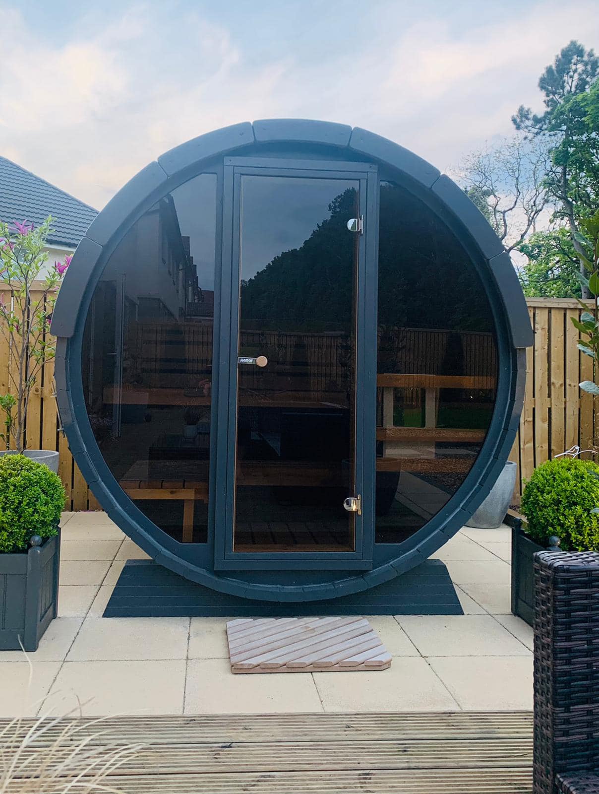 Sauna tonneau à façade vitrée sombre sur une terrasse
